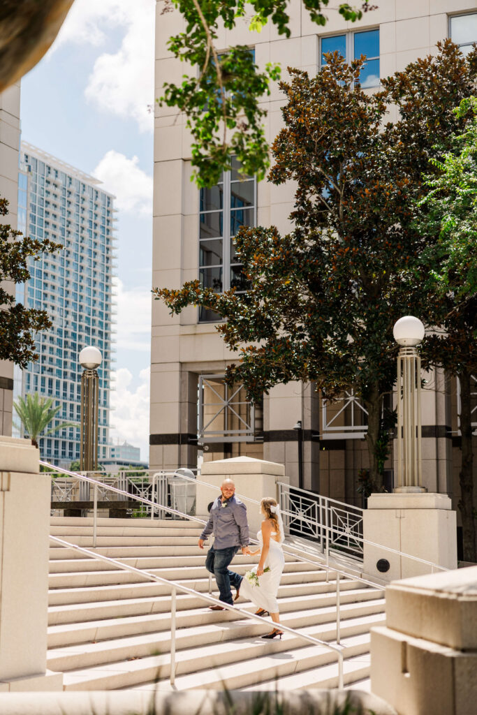 Recently eloped bride and groom walk up the steps of the Orange County courthouse in Orlando, FL. Their wedding photography package was for 3 hours a perfect amount of time for this courthouse elopement